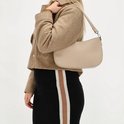 Model met taupekleurige schoudertas van Charm London op de schouder, gedragen met bruine jas en zwarte rok.