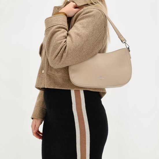 Model met taupekleurige schoudertas van Charm London op de schouder, gedragen met bruine jas en zwarte rok.