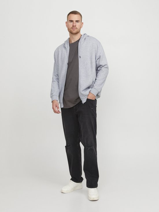 Man draagt een lichtgrijs vest met rits en capuchon over een donkergrijs T-shirt, zwarte jeans en witte sneakers.