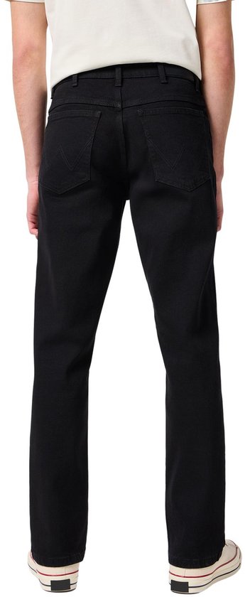Achterkant man in zwarte jeans en wit T-shirt, met beige sneakers.