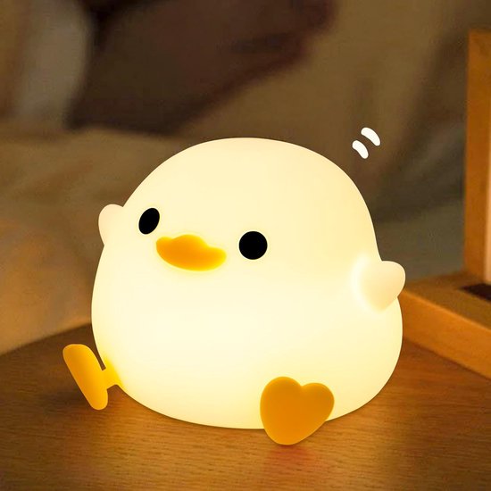 Een schattig, zacht, wit eend-nachtlampje met zwarte oogjes en een oranje snavel, dat zacht licht uitstraalt.