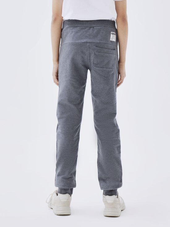 Achterkant van een jongen die een grijze joggingbroek draagt, met een wit t-shirt.
