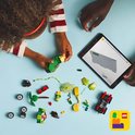 Een vrouw en een kind kijken naar een tablet terwijl ze spelen met LEGO-onderdelen.