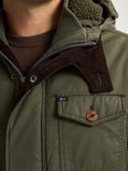 Detail van groene herenparka met bruine corduroy kraag en houten knoop op borstzak.