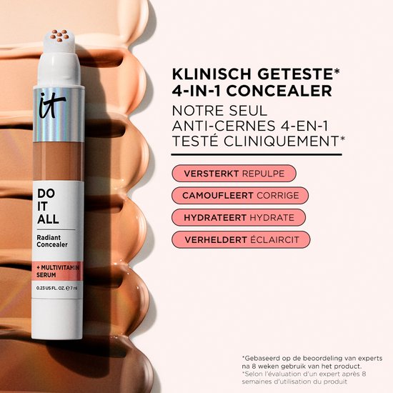 Flesje 'DO IT ALL Radiant Concealer + Multivitamin Serum' op een achtergrond van uitgesmeerde foundation. De verpakking is zilver en wit met het 'it'-logo.