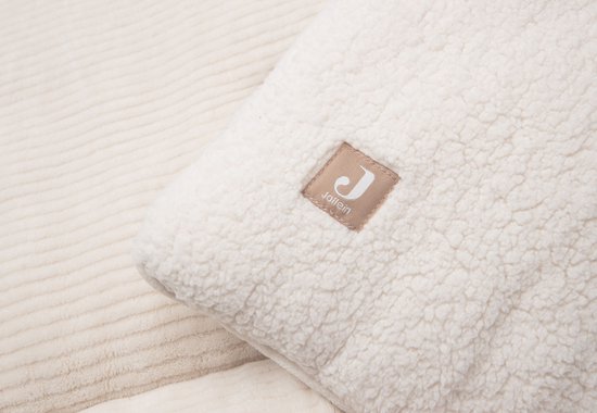 Close-up van een beige boxkleed met teddy textuur aan de ene kant en ribbelpatroon aan de andere kant, met een Jollein label.