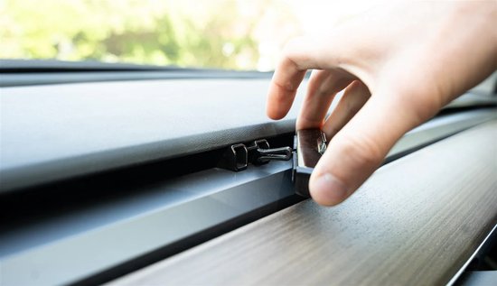 Hand bevestigt een zwarte auto-interieurparfumhouder aan een ventilatierooster.