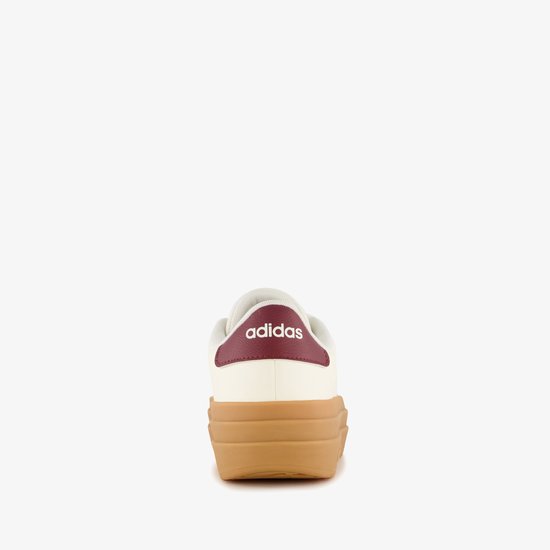 Achterkant van een witte damessneaker met bordeauxrode hiel en Adidas-logo, op een dikke bruine plateauzool.