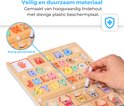 Close-up van een houten alfabetpuzzel met gekleurde letters en mandjes. Een hand gebruikt een pen.