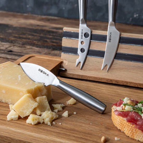 Close-up van een kaasplank met diverse kazen en toastjes, met drie kaasmessen.