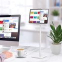 Wit tabletstandaard op een bureau met een tablet, een computer en een kopje koffie.