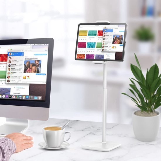 Wit tabletstandaard op een bureau met een tablet, een computer en een kopje koffie.