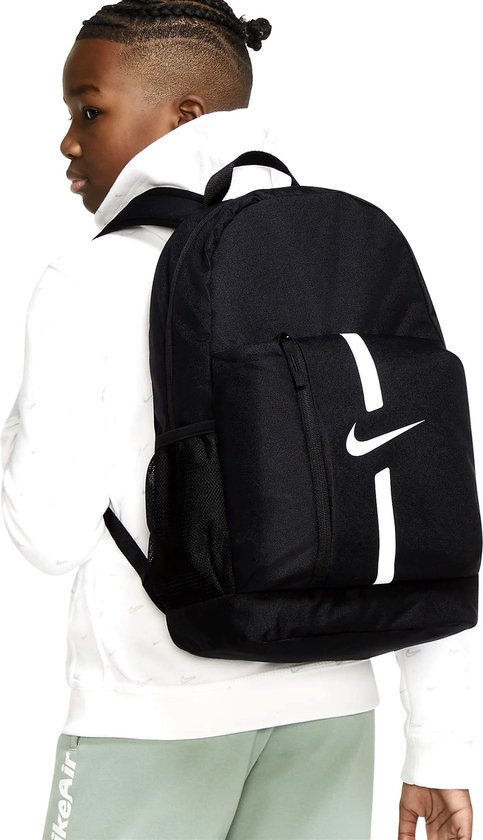 Jongen draagt zwarte Nike rugzak met witte strepen op zijn rug.