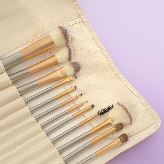 Close-up van make-up kwasten in een beige etui. Gouden en zilveren houders met witte tot bruine borstelharen.