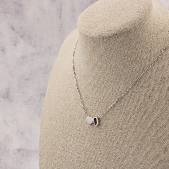Collier argenté avec un cœur et la lettre D, porté sur un mannequin.