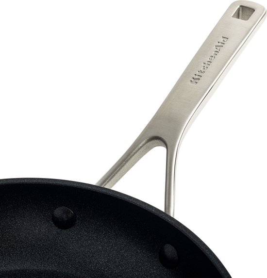 Detailopname van de roestvrijstalen handgreep met de merknaam KitchenAid op een zwarte koekenpan.