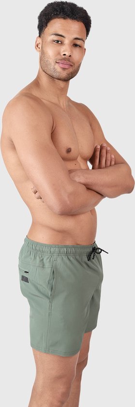 Homme en short de bain vert olive avec cordon de serrage et logo sur le côté, debout, bras croisés.