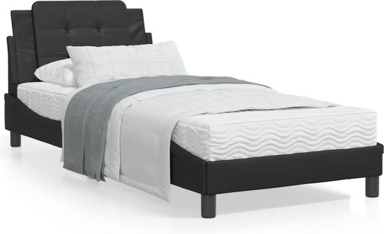 Cadre de lit noir capitonné dressé avec de la literie blanche et un jeté gris, avec un matelas blanc.