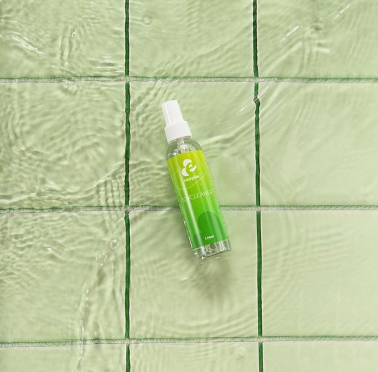 Bouteille EasyGlide Toycleaner 150 ml posée sur des carreaux verts sous de l'eau courante.