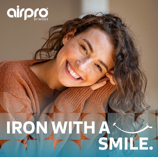 Vrouw met krullend bruin haar en sproeten glimlacht, leunend op haar handen. "Iron with a smile" is te zien.