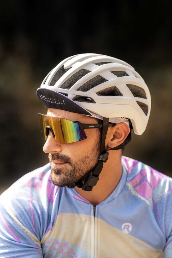 Wit Rogelli fietshelm met zwarte klep. Een man met zonnebril en baard draagt de helm.