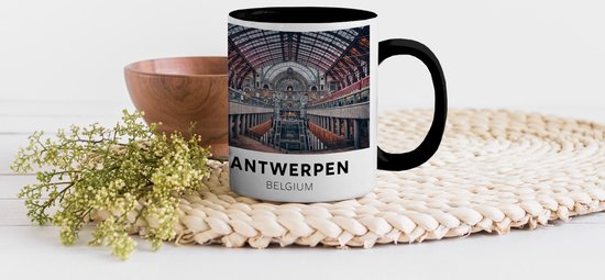 Zwarte mok met Antwerpen, België opdruk, staand naast een houten kom en plant.