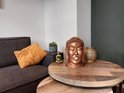 Bronzen Boeddha hoofd tissuehouder op een salontafel naast sierobjecten.