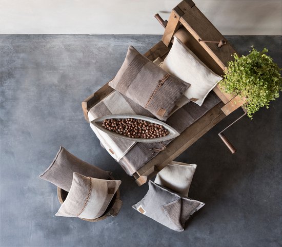 Een houten kruiwagen gevuld met gebreide kussens in bruin-, grijs- en beige-tinten.