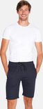 Man met witte t-shirt en donkerblauwe korte broek met trekkoord, staand en lachend.