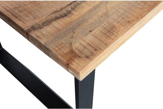 Close-up van de hoek van een houten tafelblad met een zwarte metalen poot.