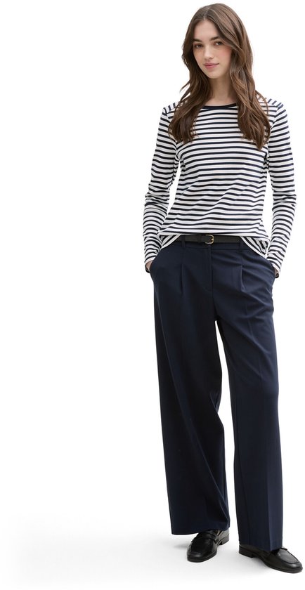 Model draagt een gestreepte longsleeve met boothals en donkerblauwe wijde pantalon met hoge taille.