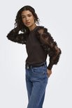 Model in bruine trui met doorschijnende, bloemige mouwen, jeans en zwarte riem.