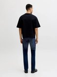 Man van achteren gezien, met zwarte T-shirt en donkerblauwe jeans.
