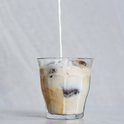 Du lait est versé dans un verre Duralex Picardie avec de la glace et du café. Le lait se mélange au café.