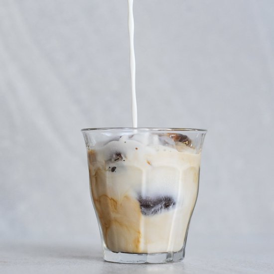 Du lait est versé dans un verre Duralex Picardie avec de la glace et du café. Le lait se mélange au café.