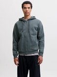 Model draagt een effen, donkergroene hoodie met ritssluiting en capuchon.