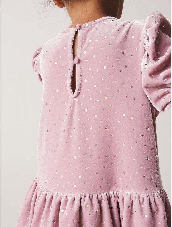 Detail van de roze fluwelen jurk met glinsterende stippen, pofmouwen en knoopsluiting aan de achterkant.
