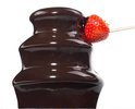 Close-up van stromende chocolade op de Princess fontein, waarbij een aardbei op een prikker in de chocolade wordt gedoopt.