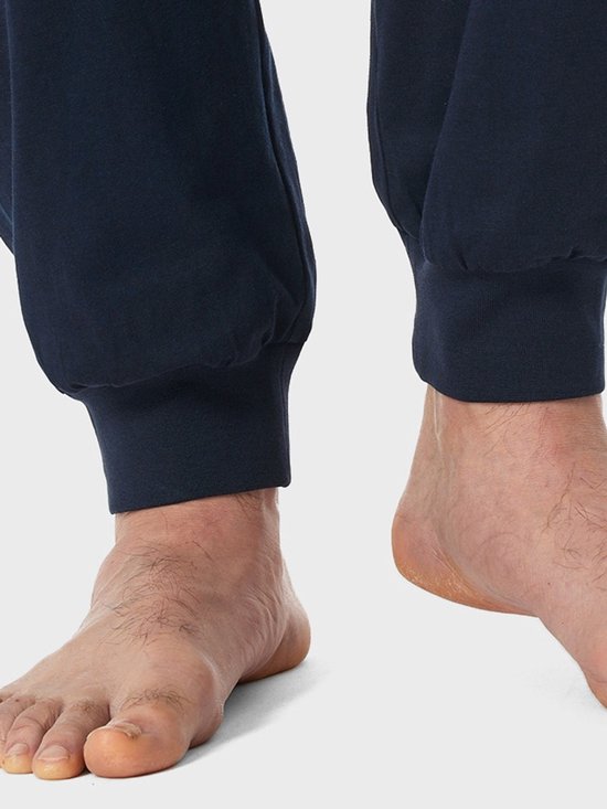 Close-up van blote voeten en de elastische boorden van een donkerblauwe pyjamabroek.