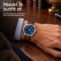 Herenhorloge met blauwe wijzerplaat, zilverkleurige kast en bruine leren horlogeband om een pols.