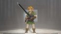 Link, met blond haar en elf-oren, draagt een groene tuniek en een schild, en houdt een groot zwaard vast.