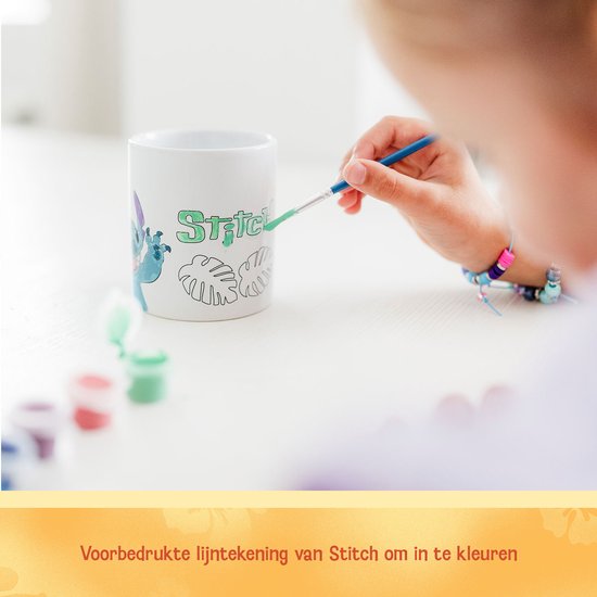 Kind schildert de voorbedrukte Stitch-lijntekening op een keramieken mok met een penseel.