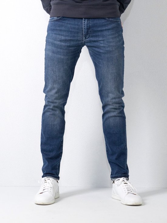 Voorkant van een man in donkerblauwe slim fit jeans.