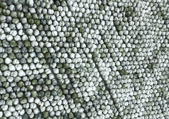 Detailopname van een badmat met textuur van witte en groene bolletjes.