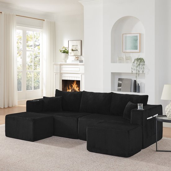 Zwarte corduroy hoekbank in een woonkamer met open haard, met bekerhouders.