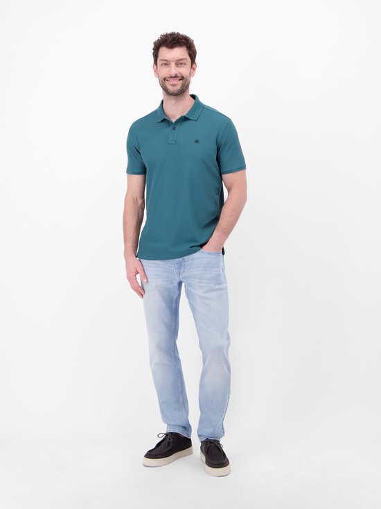 Blauwe polo met donkerblauwe kraag en knopen, model met hand in zak
