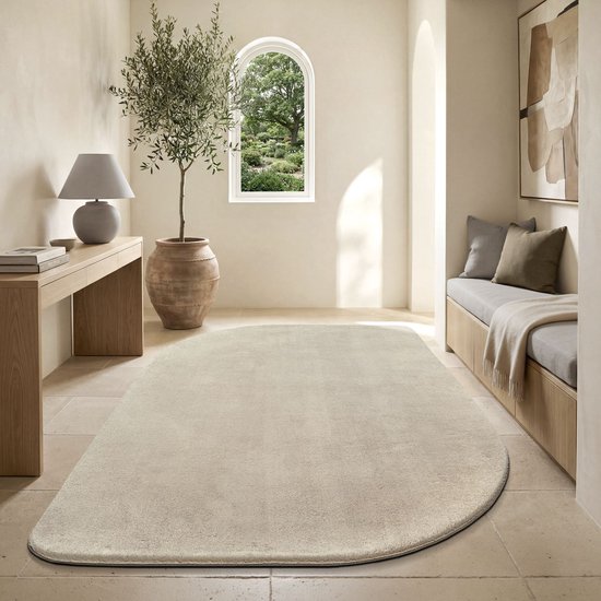 Un tapis beige allongé dans un salon moderne et lumineux avec une plante et un banc.