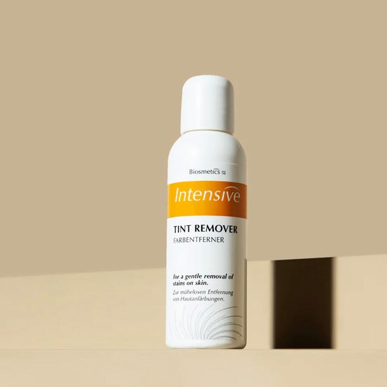 Biosmetics Intensive Tint Remover fles met witte dop op een beige achtergrond.