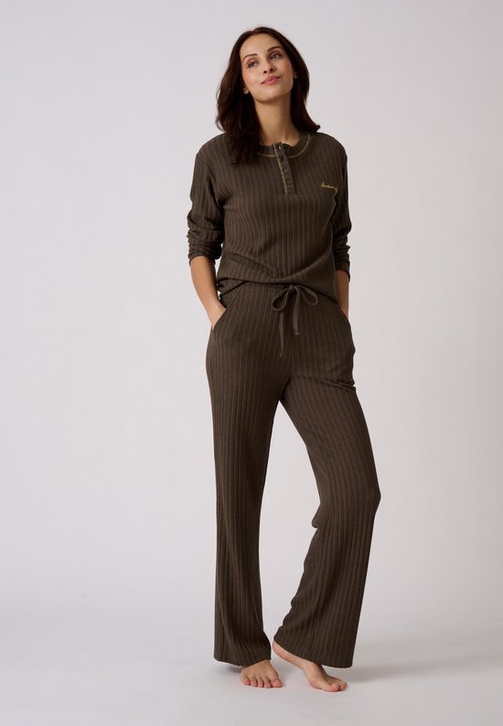 Model in bruine pyjamaset van ribtricot met lange mouwen en strikceintuur. De tekst "Serenity" staat op de borst.