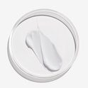 Een witte crème swatch in een petrischaal, met een dikke textuur.